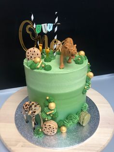 a green cake decorated with animals and plants