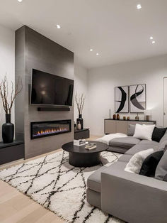 A modern living room with a fireplace, flat-screen TV, gray sectional seating, black accents, and geometric rug. Decor With Black Accents, Cozy Sectional, Sleek Fireplace, Apartment Decorating Living, Snack Organizer, Black And White Living Room, Minimalist Living Room Design, Living Room Decor Gray, Black Living Room