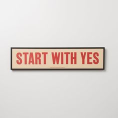 a sign that says start with yes in red and black on a white wall behind it