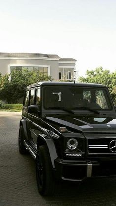 a black mercedes g - class parked in front of a house