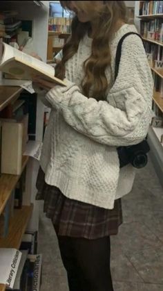 a girl is reading a book in a library with bookshelves and shelves full of books