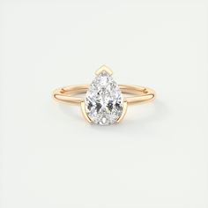 a yellow gold engagement ring with a pear shaped diamond in the center, on a white background