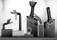 black and white photograph of various items on display in front of a gray background with one hand reaching out to the other