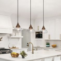 a kitchen with three lights hanging from the ceiling and white counter tops on the island