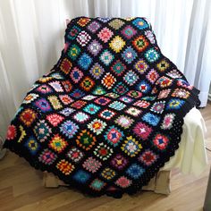 a crocheted granny blanket sitting on top of a bed next to a window