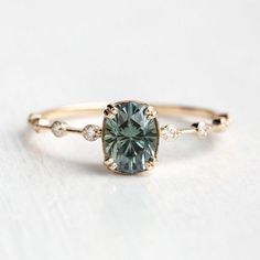 a gold ring with a green diamond in the center