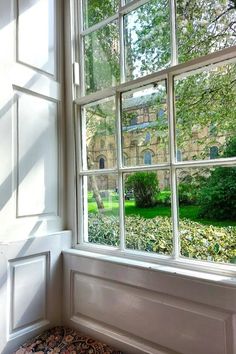 an open window with the view of a building through it's glass panes