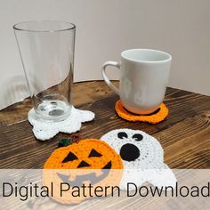 a wooden table topped with two crocheted halloween coasters and a cup holder