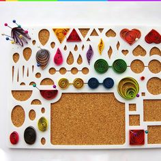 a cork board with different colored circles and shapes on it, sitting on a white surface