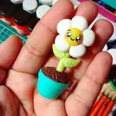 a hand holding a tiny toy flower in it's palm