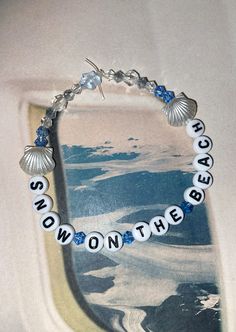 a beaded bracelet with words and seashells on the beads is displayed in front of an airplane window