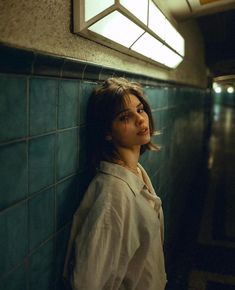 a woman leaning against a wall with her head turned to the side and eyes closed