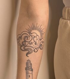 a person with a tattoo on their arm and a lighthouse in the sky behind them