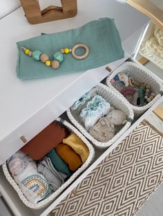 two baskets filled with baby items sitting on top of a white table next to a pillow