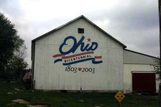 an old white barn with the word oke on it's side and american flag in the background