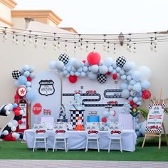 a party setup with balloons and race cars on the wall, table set up for a race car themed birthday party