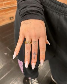 a woman's hand with tattoos on it and a gold band around her fingers