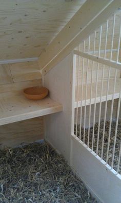 the inside of a chicken coop with hay on the floor and a bowl in the corner