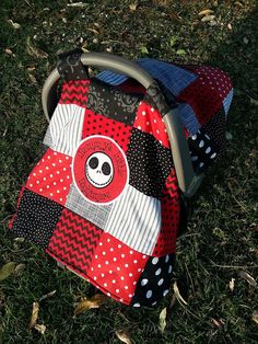 a red and black patchwork bag with a skull on it sitting in the grass