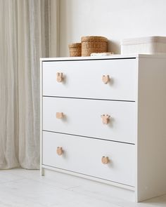 a white dresser with four drawers and two baskets on top