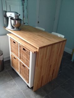 a kitchen with a wooden counter top next to a blender on a stand near a trash can