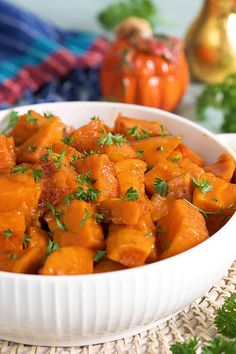 a white bowl filled with cooked carrots on top of a table