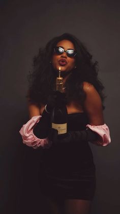 a woman holding a bottle of wine in front of her face with sunglasses on it