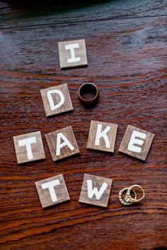 the word i do take two spelled out of wood blocks with wedding rings next to it