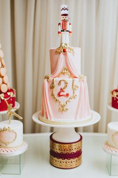 a pink and gold wedding cake sitting on top of a table next to other cakes