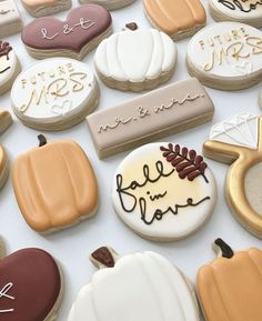 many decorated cookies are displayed on a white tablecloth with writing and pumpkins in the background