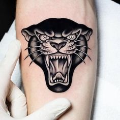 a black and white tattoo of a panther on the left arm with its mouth open