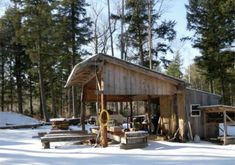 a wooden building in the middle of snow covered ground with lots of trees around it