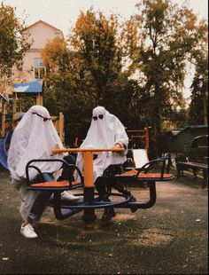 two people sitting on park benches covered in white cloths