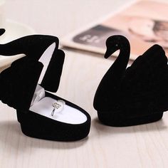 two black swan shaped rings are sitting on a table