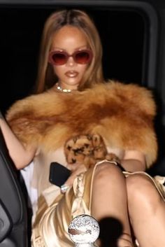 a woman sitting in the back seat of a car wearing a gold dress and fur stole