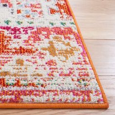 an orange and white area rug on a wooden floor with wood floors in the background