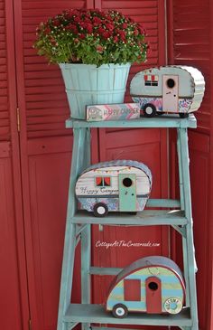 an old ladder has some flowers in a pot on top and a toy camper next to it