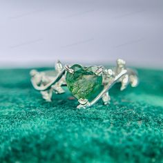 a green heart shaped ring sitting on top of a green blanket