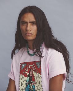 a woman with long hair wearing a pink t - shirt and beaded necklaces