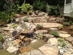 there is a small waterfall in the middle of this rock and stone garden pond area