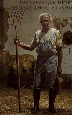 an old man holding a pitchfork in front of a sign