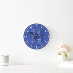 a blue clock sitting on top of a white table next to a vase with flowers