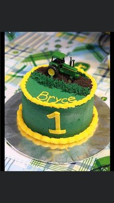 a green cake with yellow icing and a tractor on the top is sitting on a table