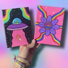 two handmade notebooks with colorful designs on them, one has an alien spaceship and the other has a rainbow flower