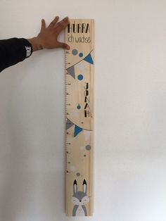 a person is holding up a wooden ruler with an animal design on the front and sides