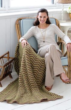 a woman sitting in a chair with a blanket