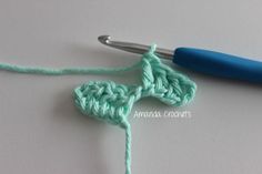 the crochet pattern is being worked on with a blue handled crochet hook