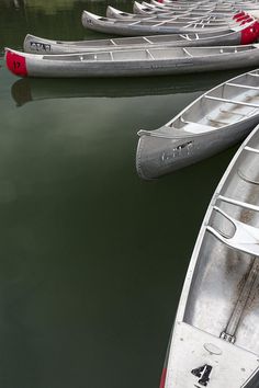 several canoes are lined up in the water near each other, and one is empty