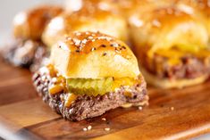 two hamburger sliders with cheese and pickles on a cutting board, ready to be eaten