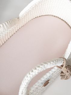 a close up of a white crocheted bed with a light pink pillow on it